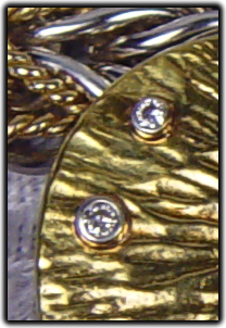 Two white diamonds set in the 24-karat gold textured overlay. 